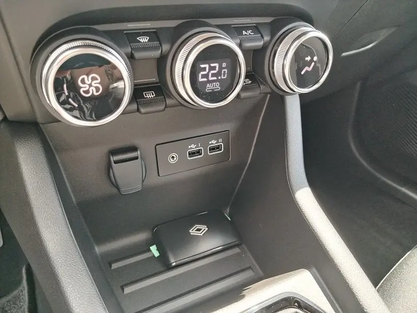 Vue rapprochée de la console centrale de la Renault Clio V TCE 90 Evolution 2026, avec commandes de climatisation et ports USB.