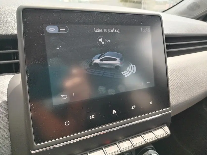 Écran tactile intérieur montrant l'aide au parking de la Renault Clio V gris Rafale, vue de face du tableau de bord.
