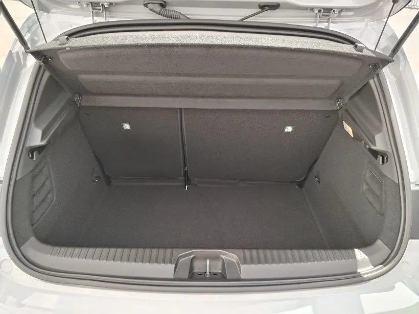 Coffre ouvert vu de l'arrière d'une Renault Clio V TCE 90 Evolution gris Rafale, montrant l'espace de chargement vide.