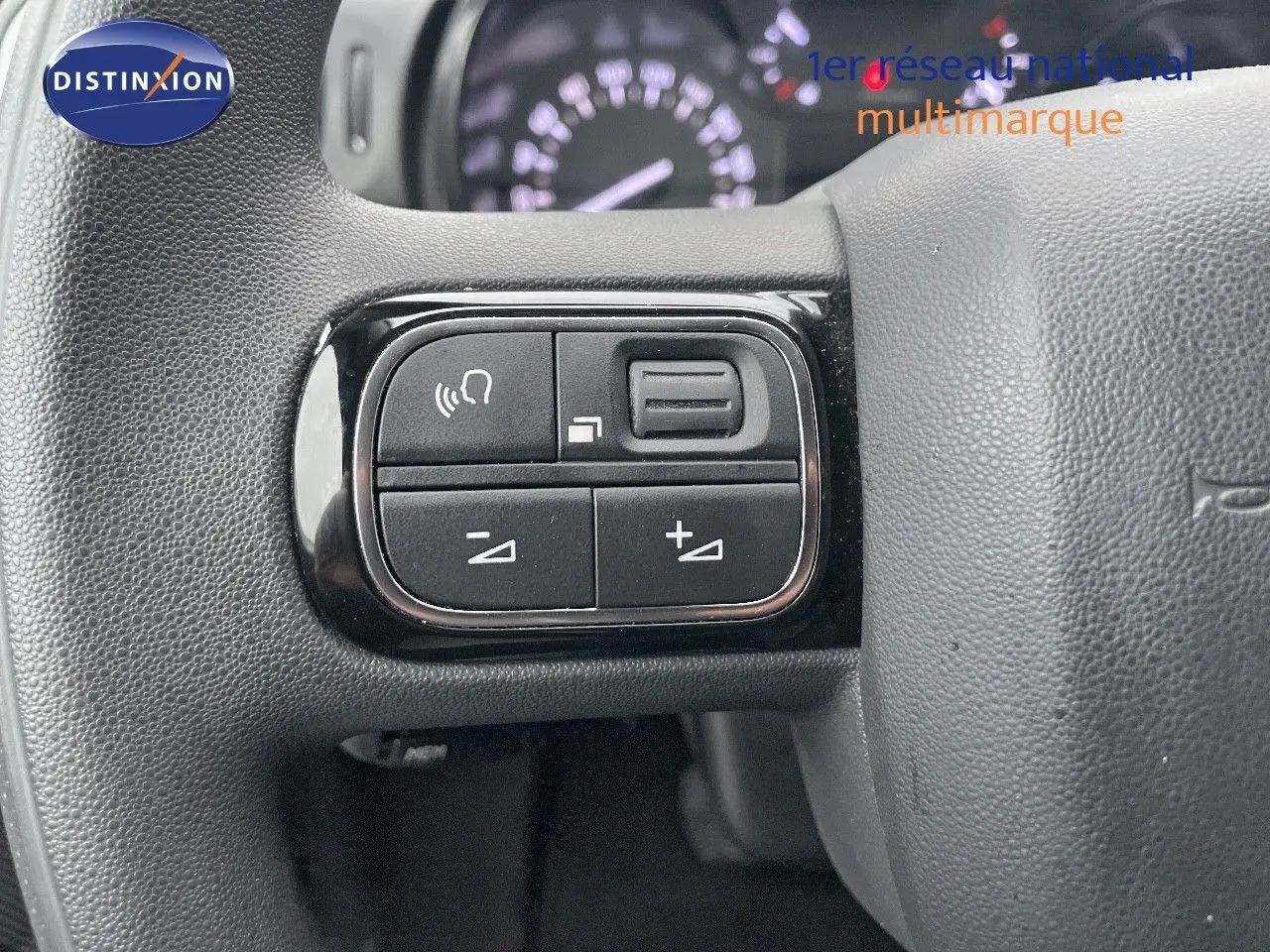 Gros plan sur les commandes de volume au volant d'une Citroën C3 gris acier avec toit noir, version Shine 2023.