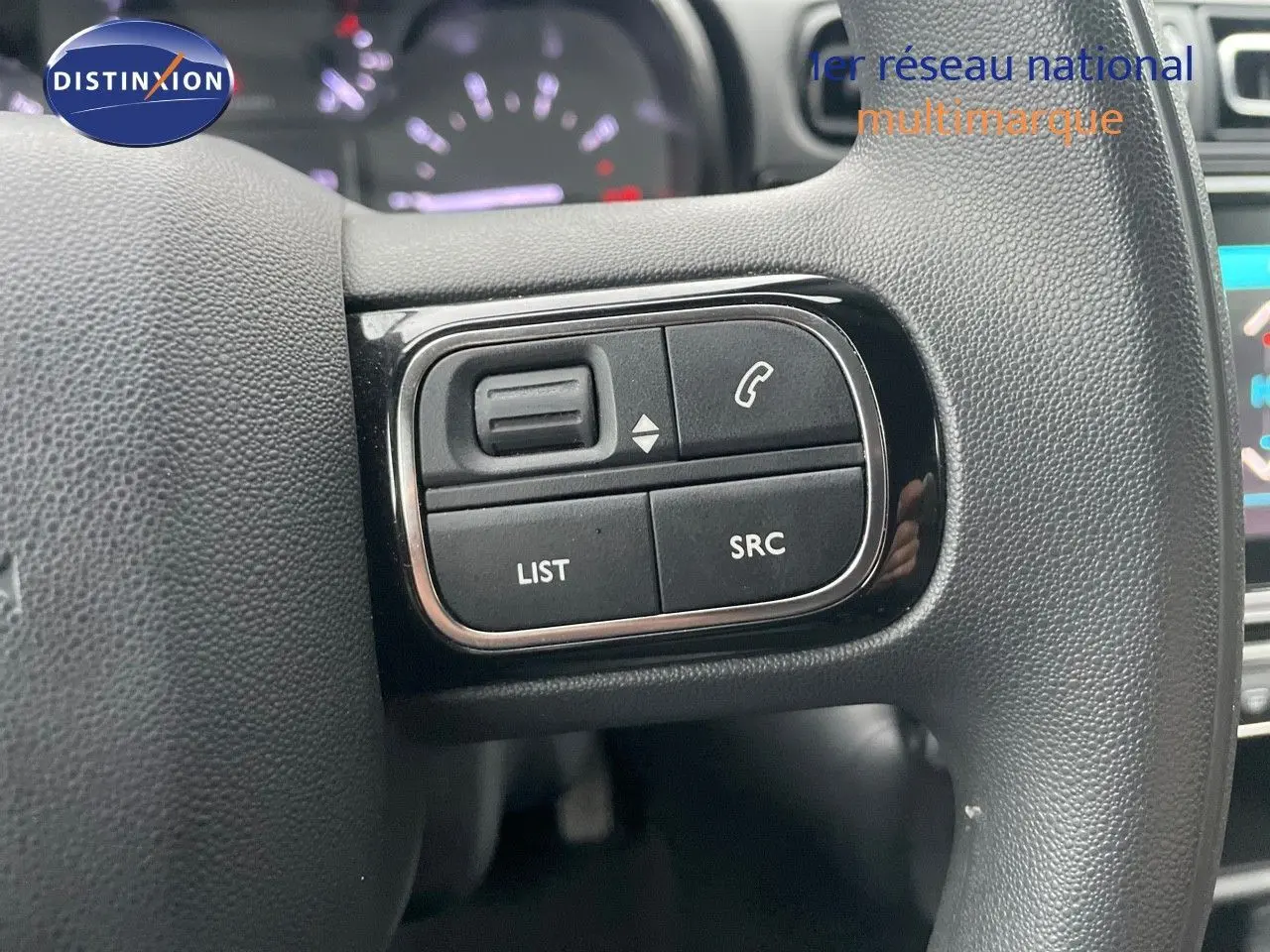 Gros plan sur les commandes gauche du volant en cuir noir de la Citroën C3 2023 gris acier métal avec toit noir.