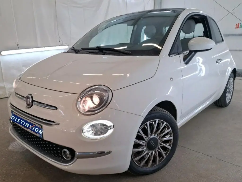 Vue 3/4 avant droite d'une Fiat 500 blanche 2022 avec phares allumés et jantes multibranches distinctives.