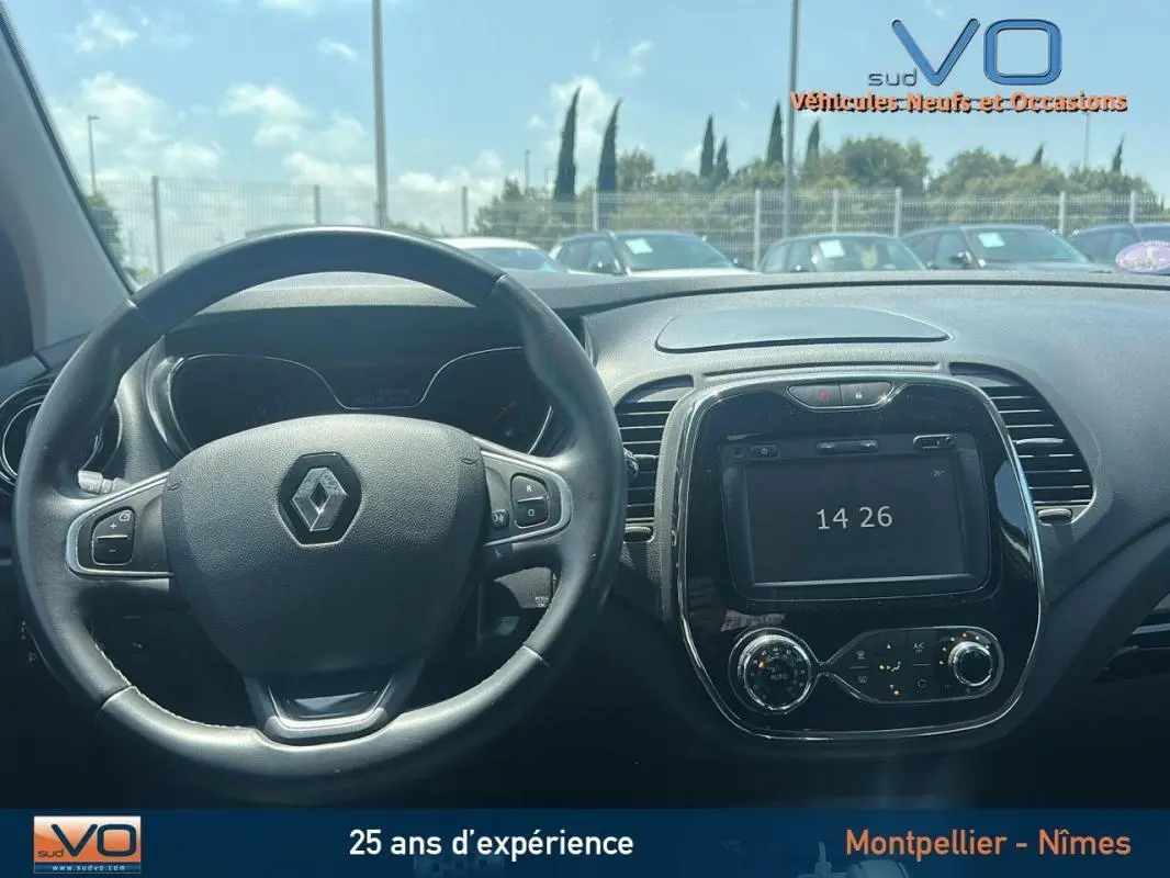 Vue intérieure du tableau de bord du Renault Captur gris clair 2016 avec volant cuir et écran tactile central.