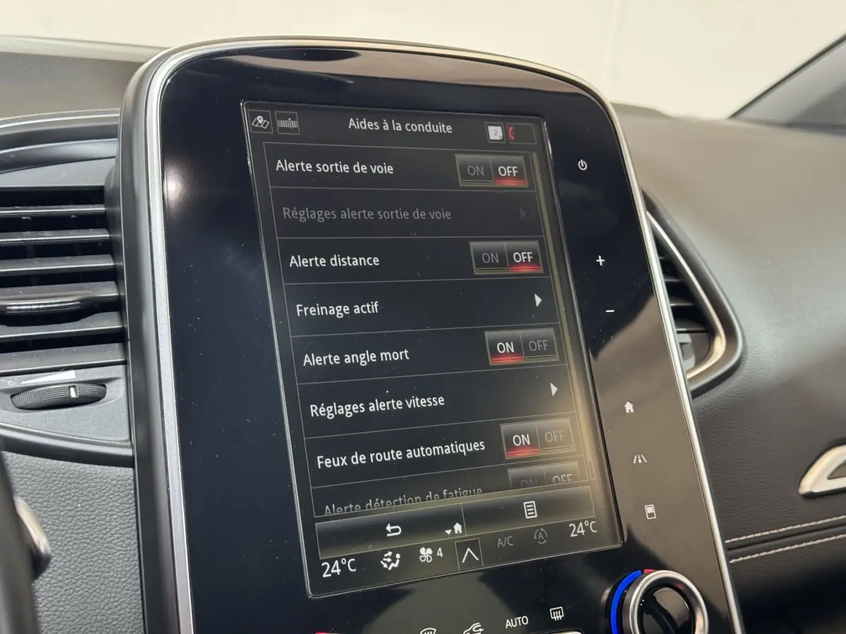 Gros plan sur l'écran tactile central du tableau de bord du Renault Scénic Intens rouge 2021 affichant les aides à la conduite.