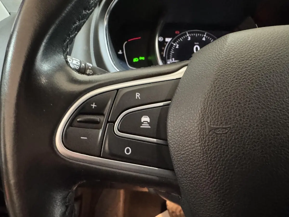 Gros plan sur les commandes du volant cuir noir du Renault Scénic Intens 2021, avec tableau de bord numérique en arrière-plan.