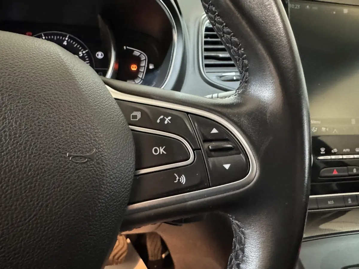 Gros plan sur le volant cuir noir côté gauche du Renault Scénic Intens TCe 160 EDC 2021 avec commandes intégrées.
