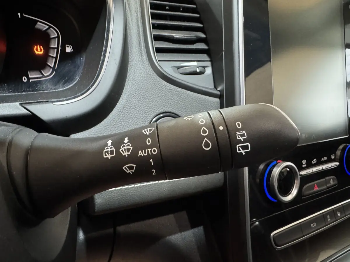 Gros plan sur la commande d'essuie-glace noire dans l'habitacle du Renault Scénic Intens rouge 2021, avec tableau de bord et écran tactile visibles.