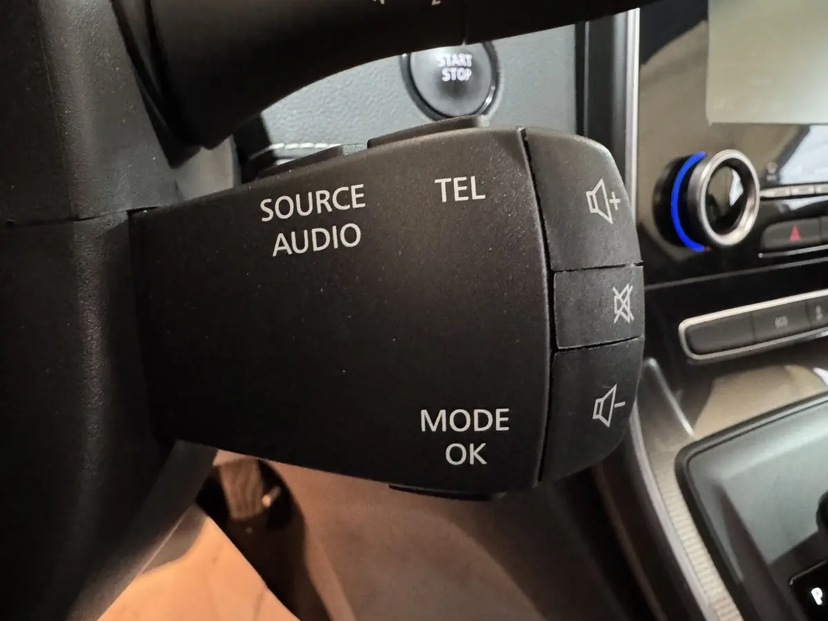 Gros plan sur la commande audio au volant du Renault Scénic Intens rouge 2021, avec bouton démarrage visible en arrière-plan.