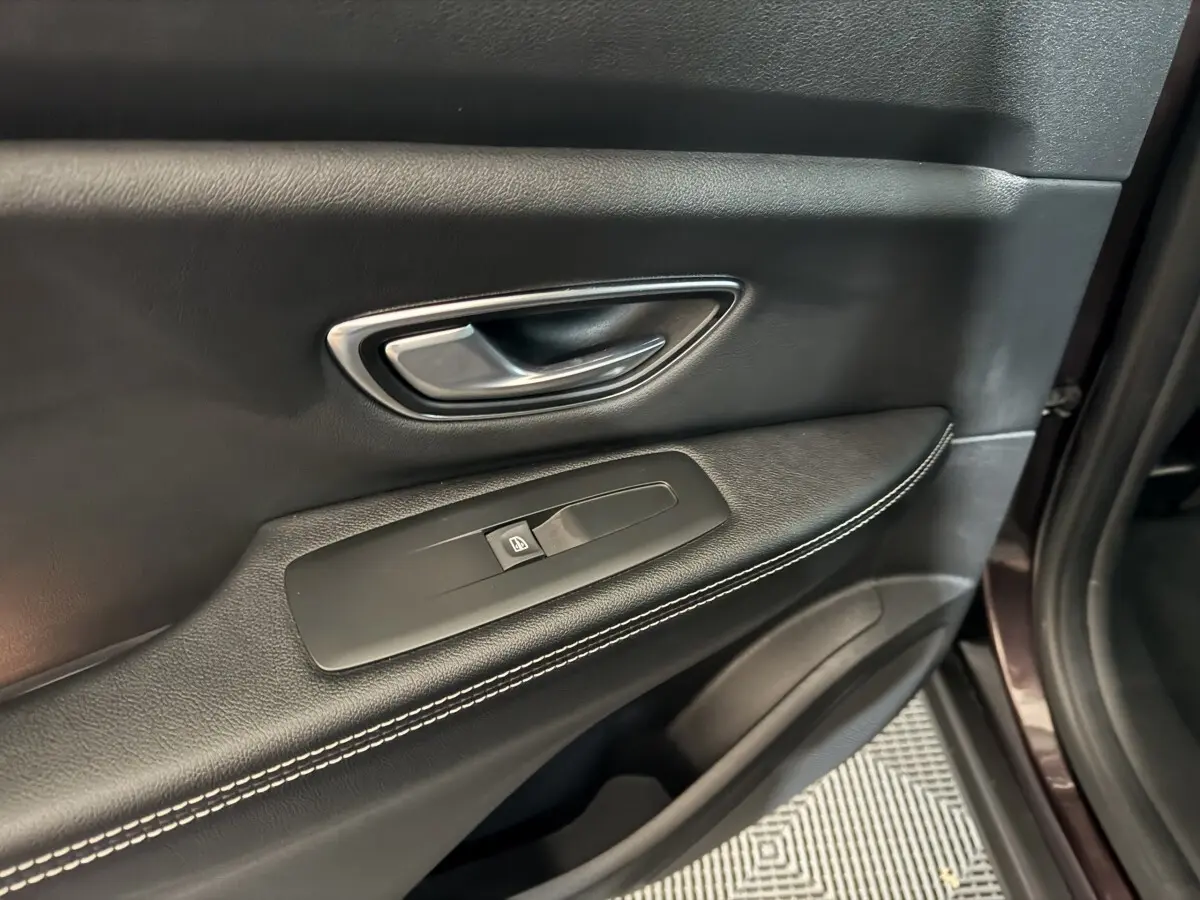 Poignée intérieure et commande de lève-vitre sur la porte avant droite en cuir noir avec surpiqûres blanches du Renault Scénic Intens rouge 2021.