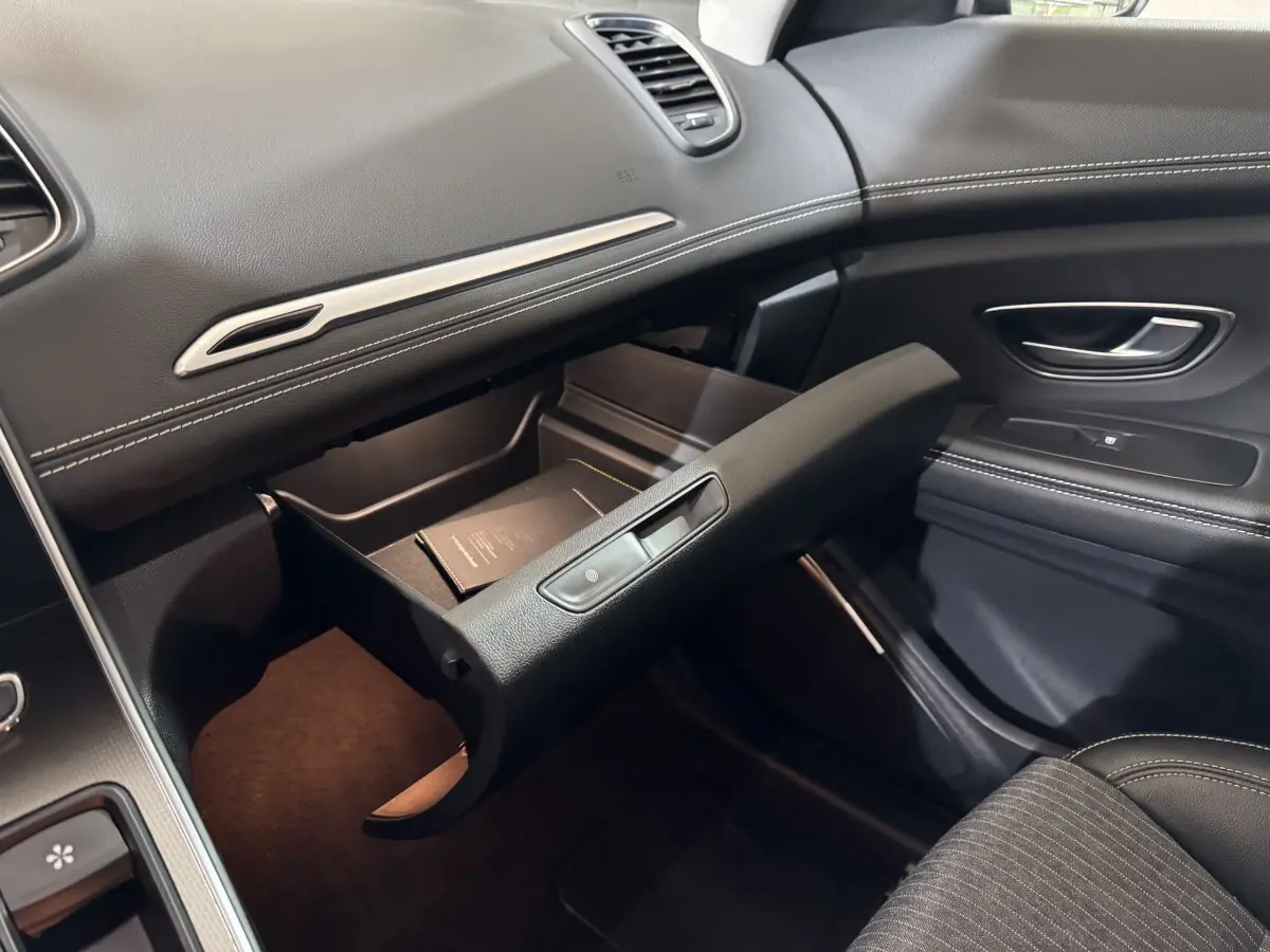 Intérieur noir du Renault Scénic Intens 2021, vue côté passager avec boîte à gants ouverte et détails coutures blanches.