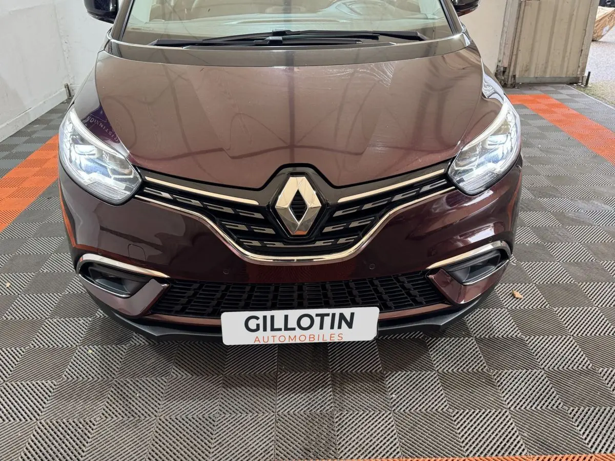 Vue frontale rapprochée du Renault Scénic Intens rouge 2021 avec phares LED allumés et calandre chromée.