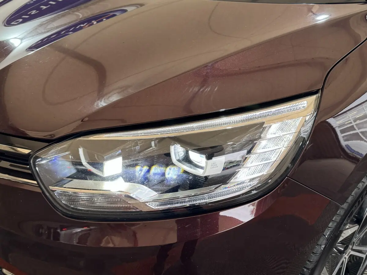 Gros plan sur le phare avant droit LED du Renault Scénic Intens rouge foncé 2021, soulignant ses détails modernes.