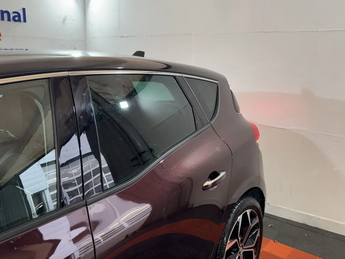 Vue côté arrière droit du Renault Scénic Intens TCe 160 rouge, mettant en valeur la porte et la jante au design moderne.