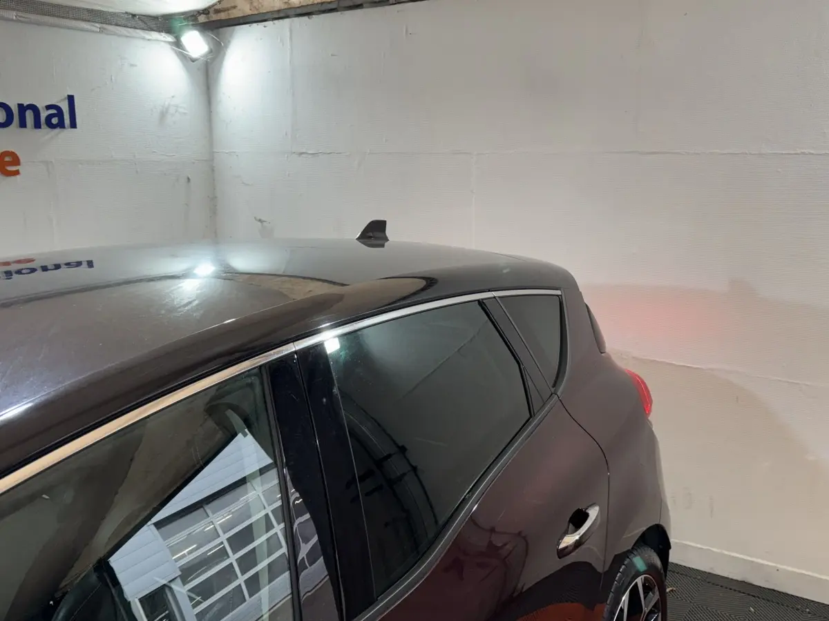 Vue 3/4 arrière droit d'un Renault Scénic Intens TCe 160 rouge avec toit noir et vitres teintées.