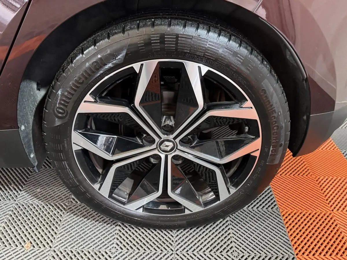 Gros plan sur la roue avant droite du Renault Scénic Intens rouge 2021 avec jante alliage noire et argentée.