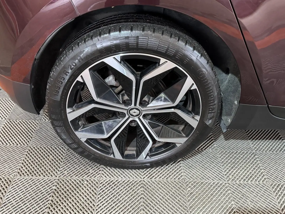 Gros plan sur la roue arrière droite rouge d’un Renault Scénic Intens 2021 avec jante alliage noire et argentée.