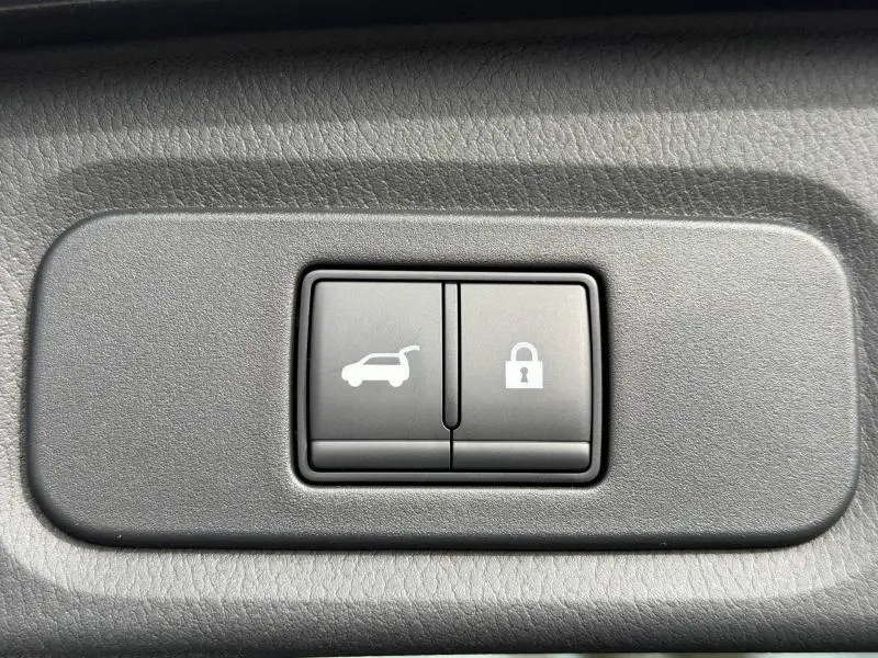 Gros plan sur les boutons d'ouverture du coffre et de verrouillage, intérieur gris texturé du Nissan Qashqai Hybrid e-POWER.