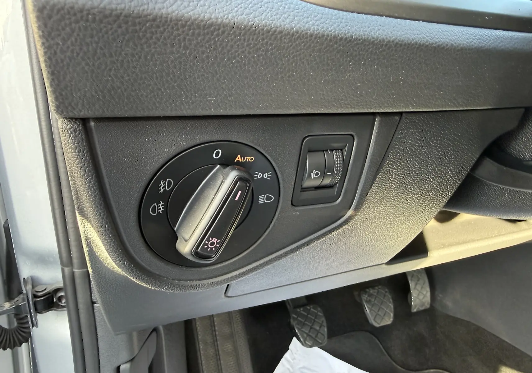 Gros plan sur le bouton de commande des phares noir dans l'habitacle gris d'une Volkswagen Polo 1.0 TSI 95 Lounge Business 2021.
