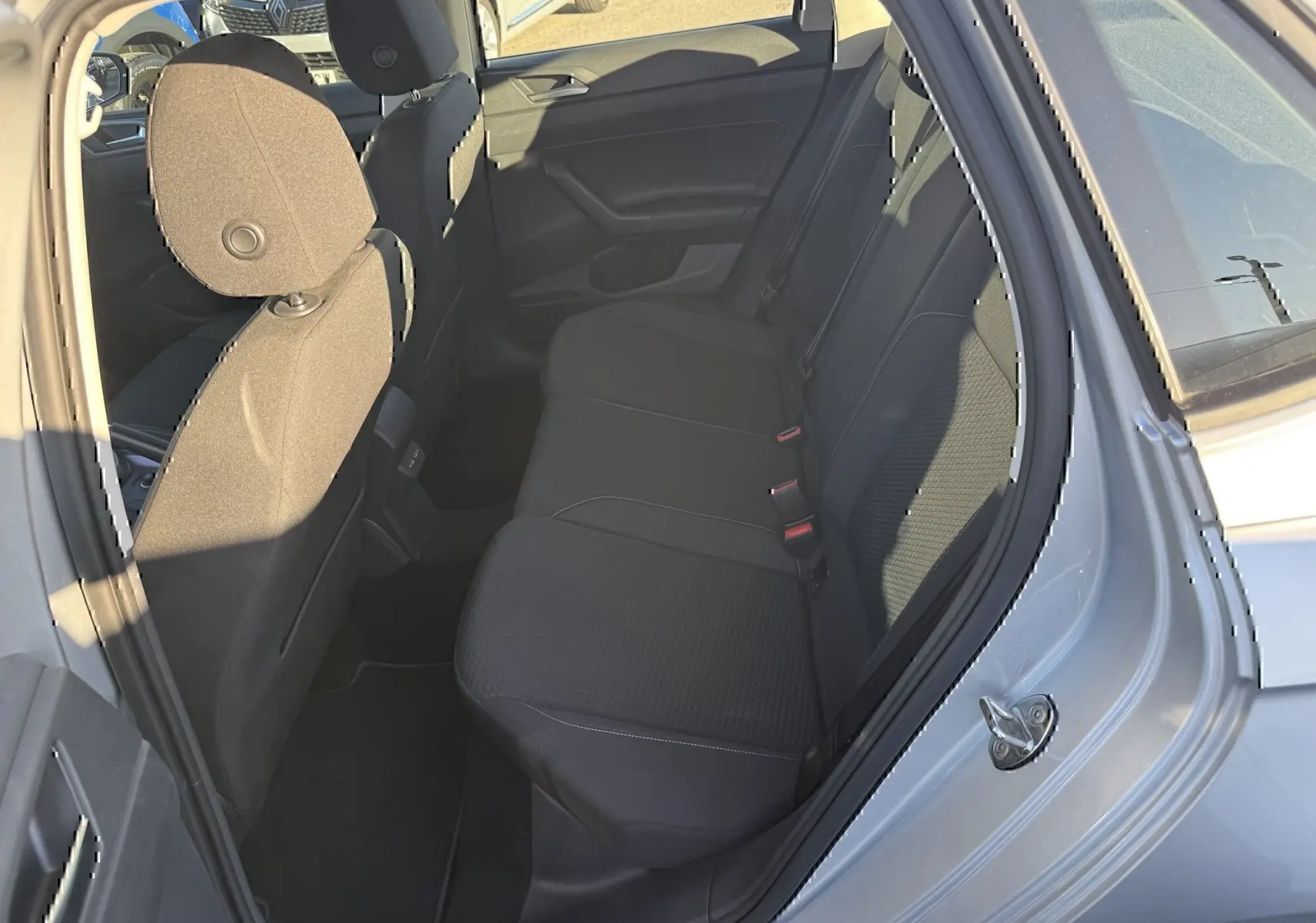 Vue intérieure côté droit sur les sièges arrière noirs d'une Volkswagen Polo gris métal 2021, porte ouverte.