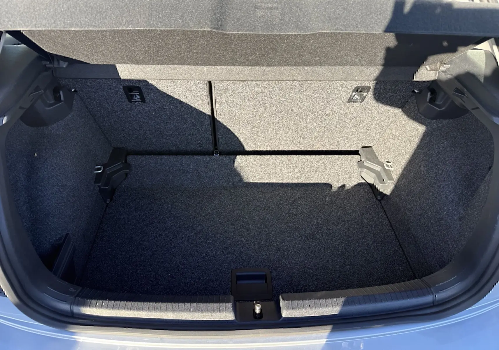 Coffre ouvert vu de l'arrière d'une Volkswagen Polo gris métal 2021, montrant l'espace de chargement vide et doublé de moquette.