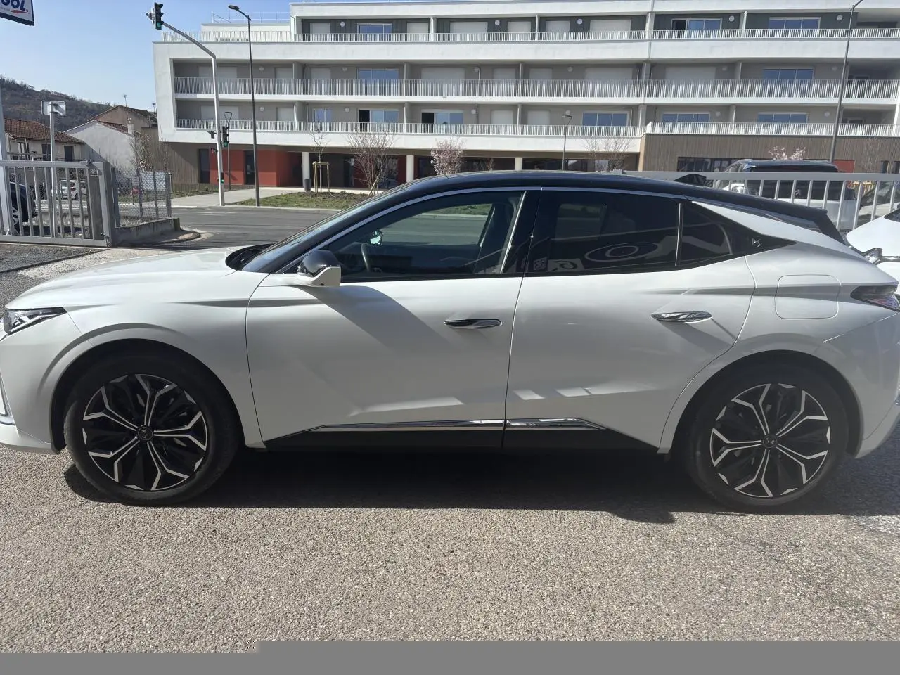 Vue latérale gauche d'une DS4 2023 blanche avec toit noir et jantes alliage noires au design distinctif.