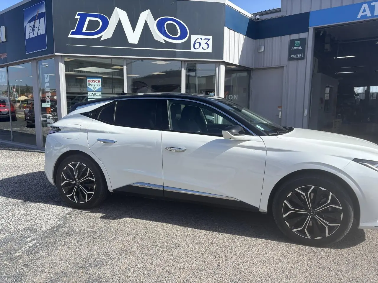 Vue latérale droite d'une DS4 2023 blanche avec toit noir Perla Nera, jantes alliage et poignées affleurantes chromées.