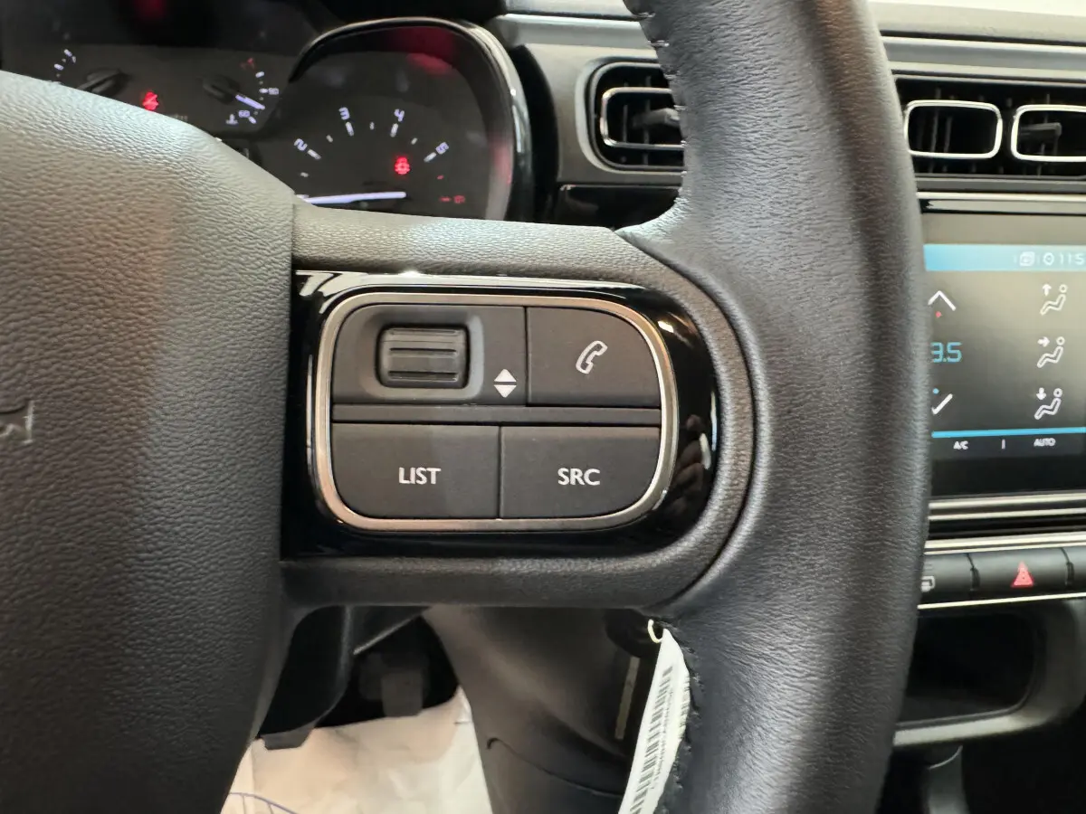 Gros plan sur le volant cuir noir de la Citroën C3 2020, avec commandes audio et téléphone intégrées.