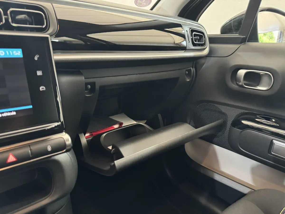 Vue intérieure côté passager de la Citroën C3 gris foncé 2020, boîte à gants ouverte avec tableau de bord noir brillant.