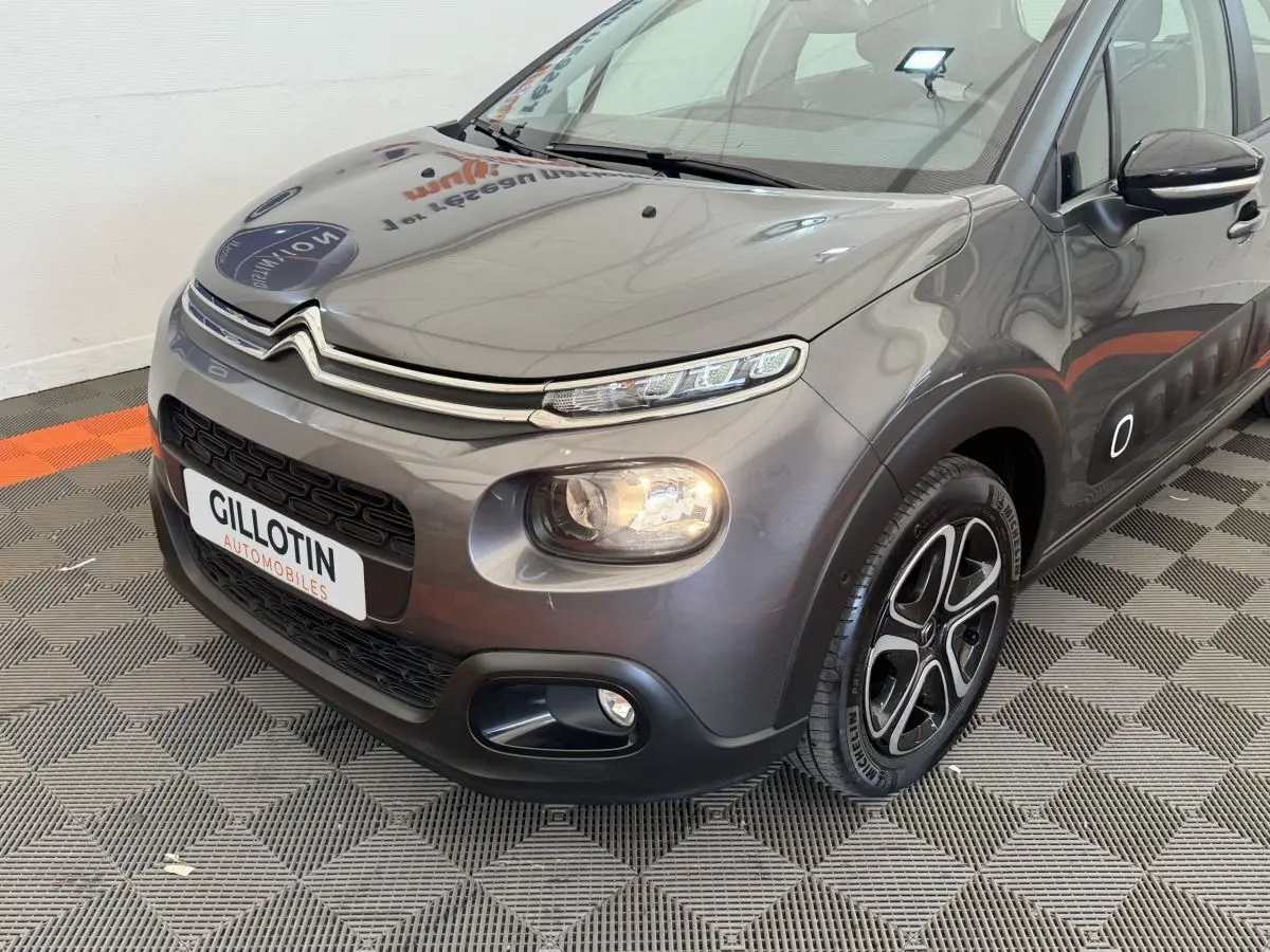 Vue 3/4 avant droit d'une Citroën C3 gris foncé avec phares LED et jantes alliage distinctives.