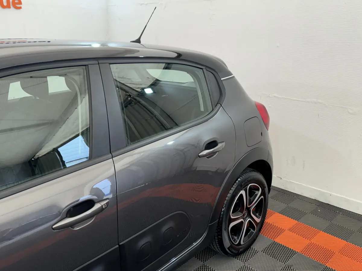 Vue côté arrière droit d'une Citroën C3 gris foncé avec jantes alliage et protections latérales noires.