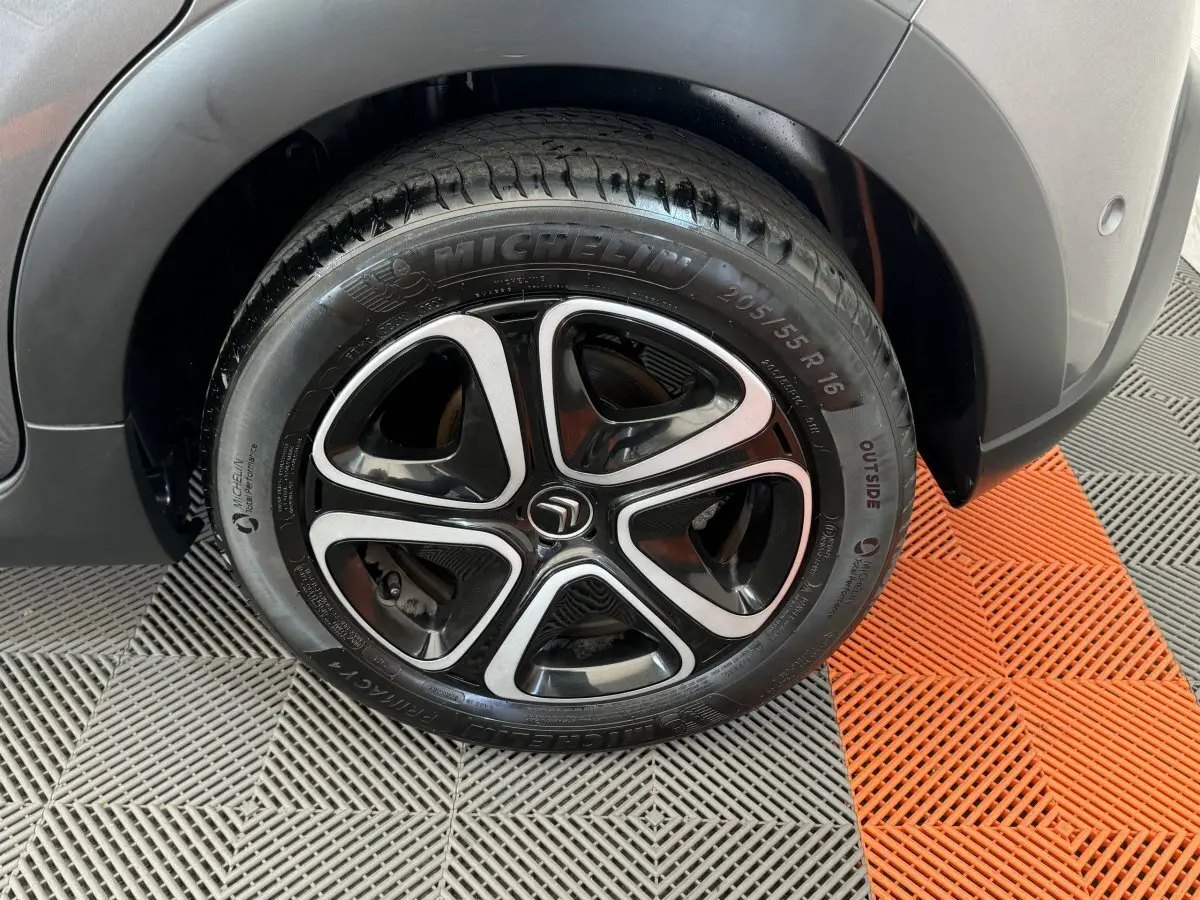 Gros plan sur la roue avant droite de la Citroën C3 gris foncé, avec jante alliage noire et argentée distinctive.