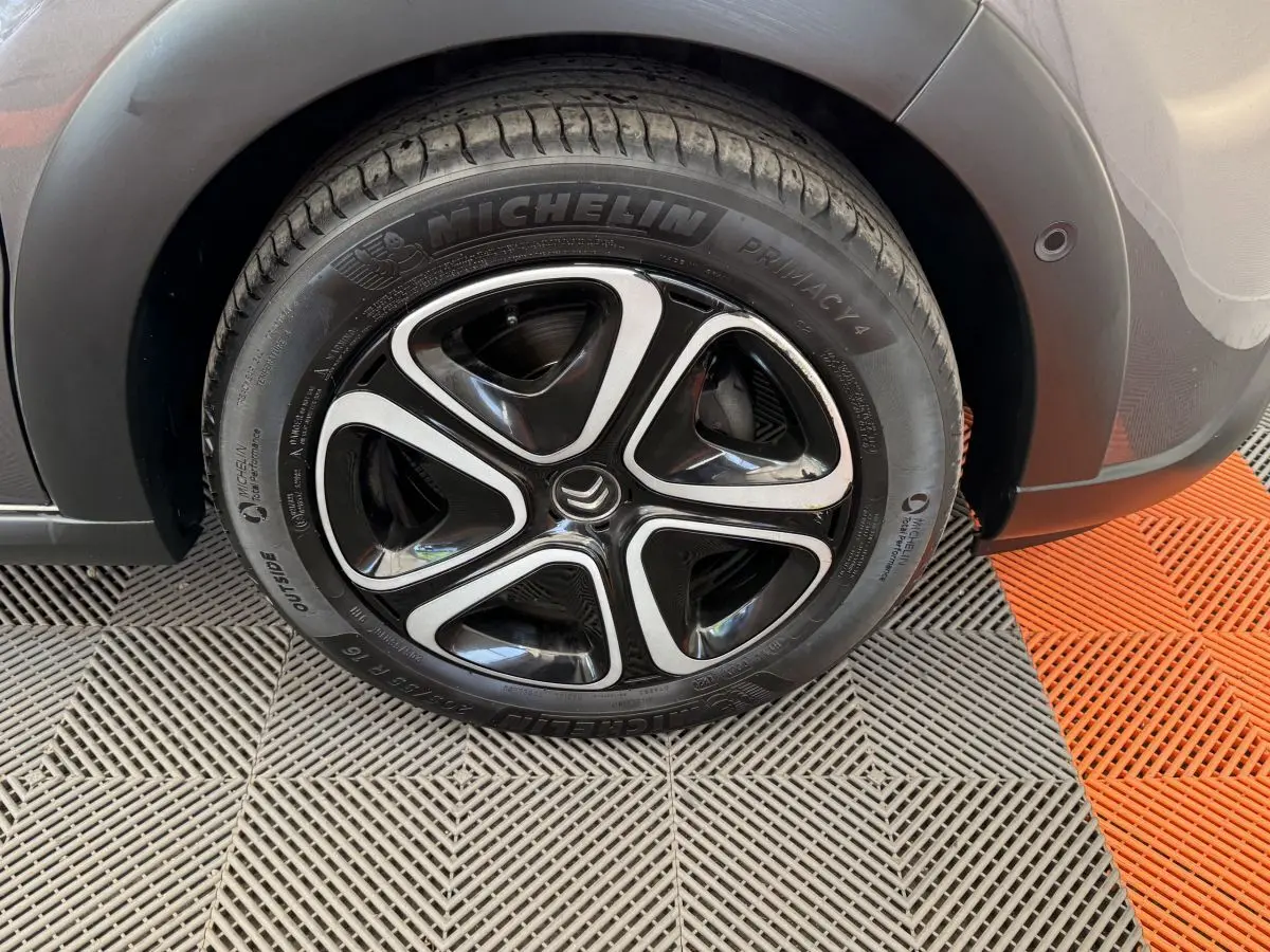 Gros plan sur la roue avant droite d’une Citroën C3 gris foncé, avec jante noire et argentée au design moderne.