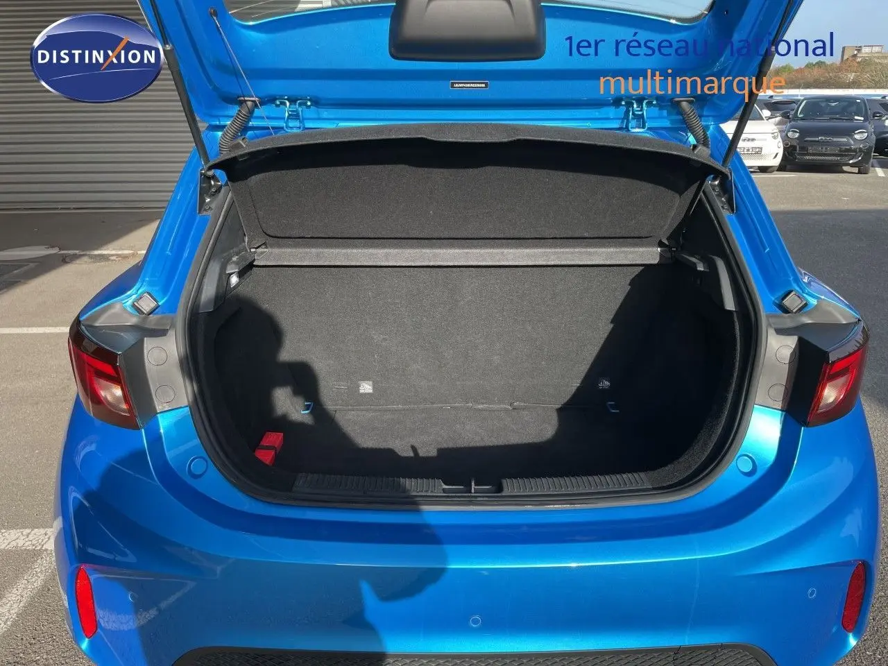 Coffre ouvert vu de l’arrière d’une MG3 1.5L HYBRID+ 195CH COMFORT en bleu Como Metal, avec intérieur de coffre noir vide.