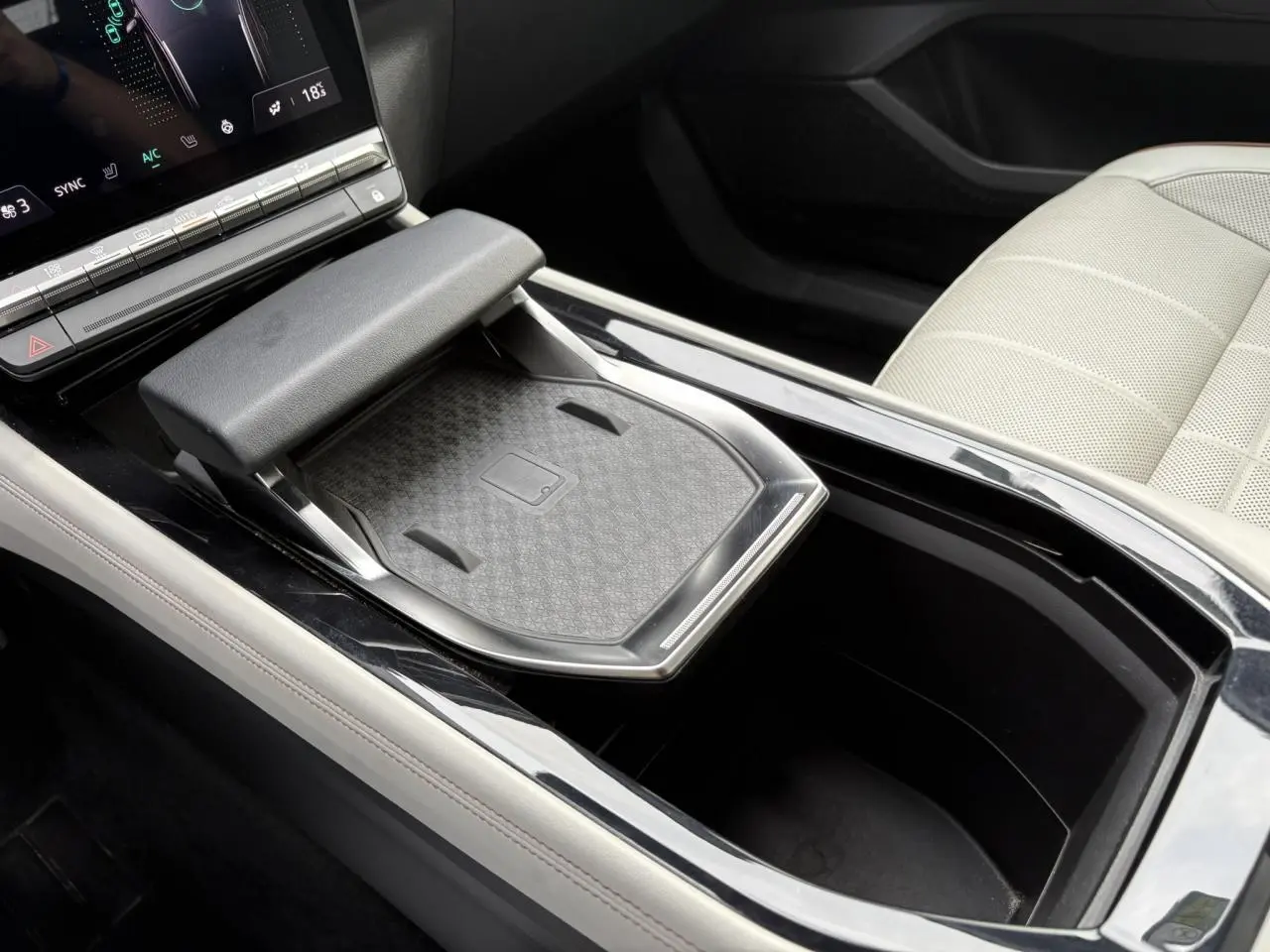 Gros plan sur la console centrale du Renault Espace VI hybride 2023, avec chargeur sans fil et sellerie cuir gris sable clair.