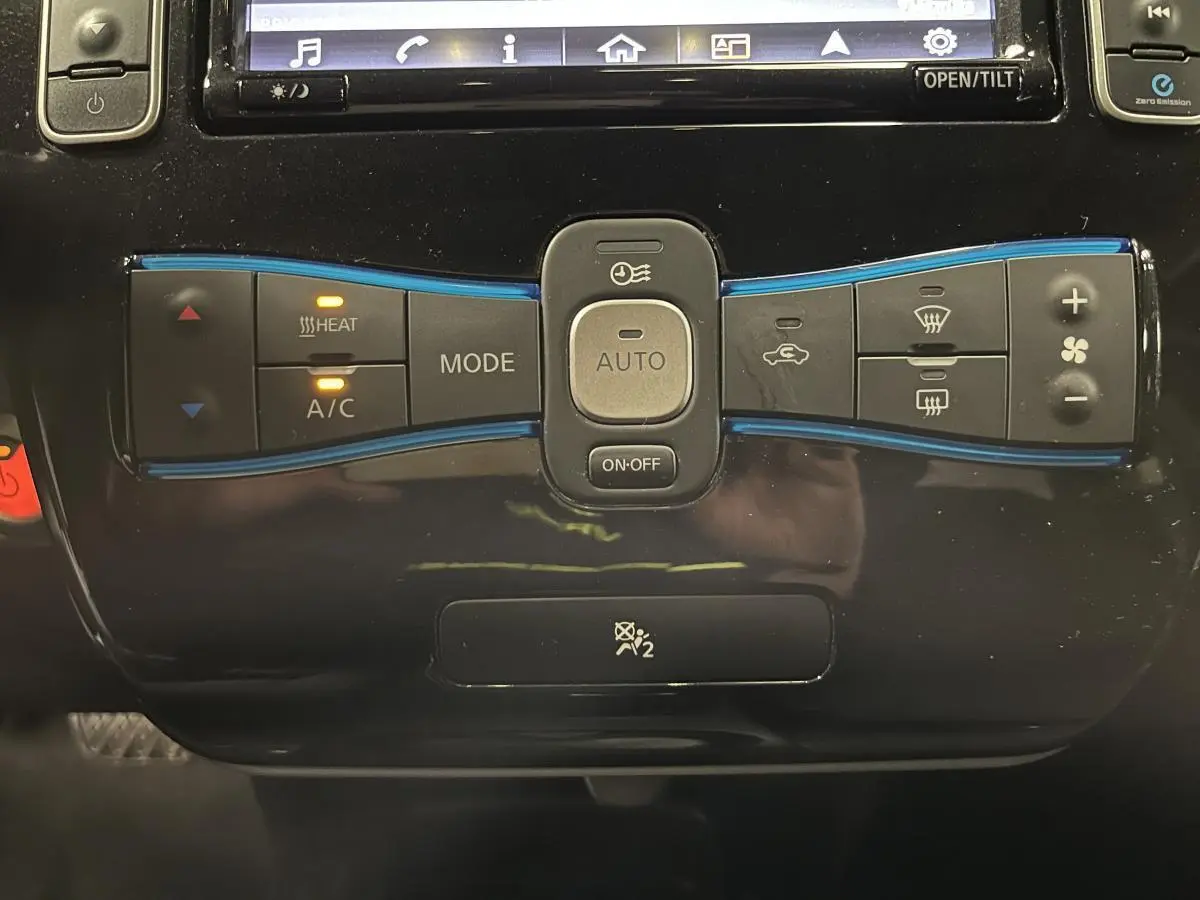Panneau de commande de climatisation automatique noir de la Nissan Leaf 30 2017 Visia avec boutons éclairés en orange.