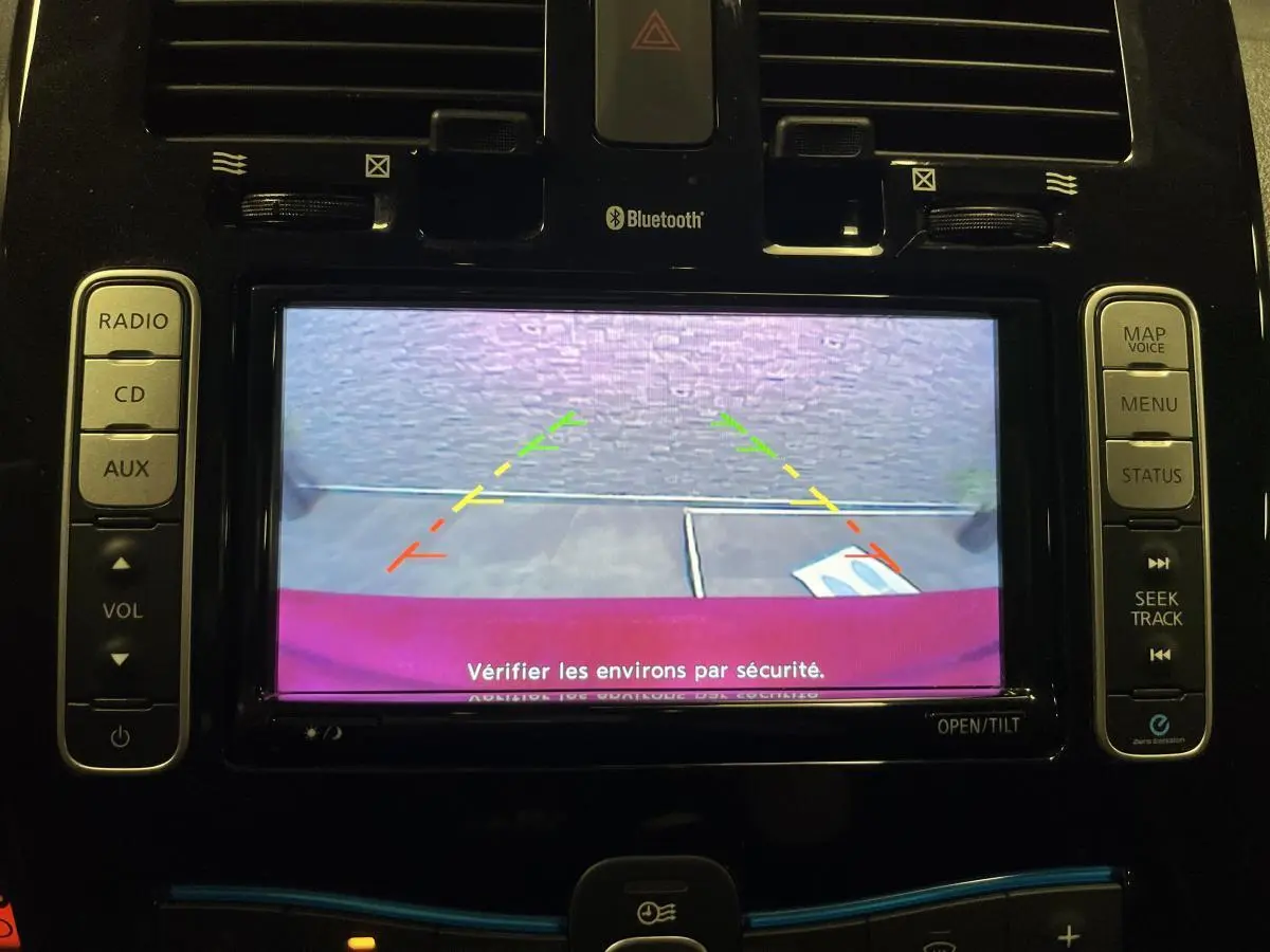 Vue de l'écran de recul du Nissan Leaf rouge 2017, affichant les lignes de guidage colorées pour la marche arrière.