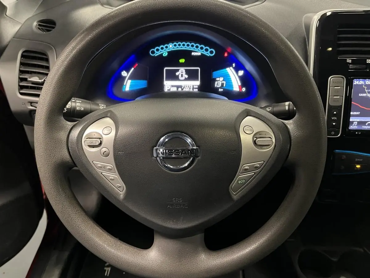 Vue rapprochée du volant Nissan Leaf 2017 avec commandes intégrées et tableau de bord numérique éclairé en bleu.