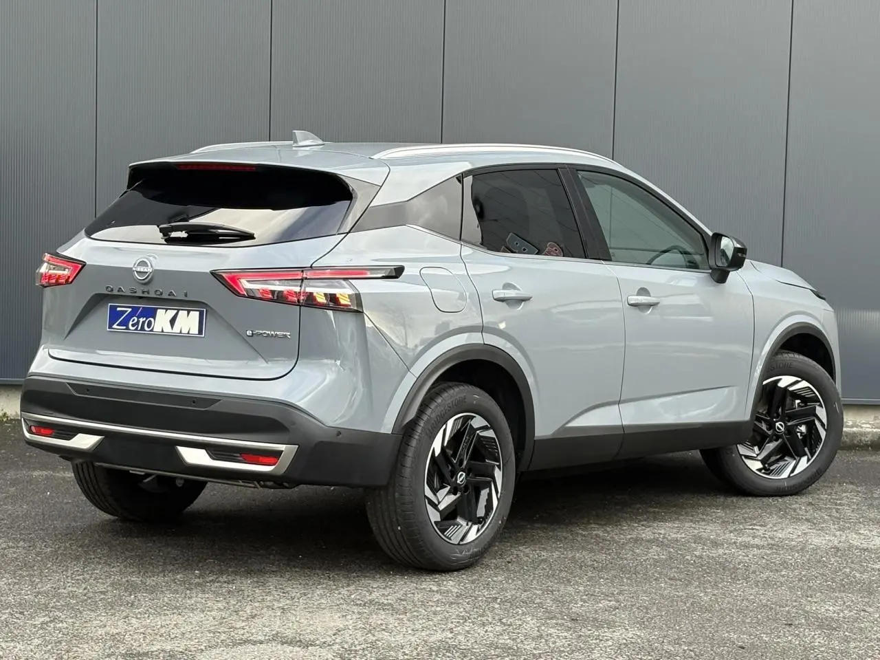 Vue 3/4 arrière droite du Nissan Qashqai III e-Power gris Ceramic avec jantes alliage noires et feux LED distinctifs.