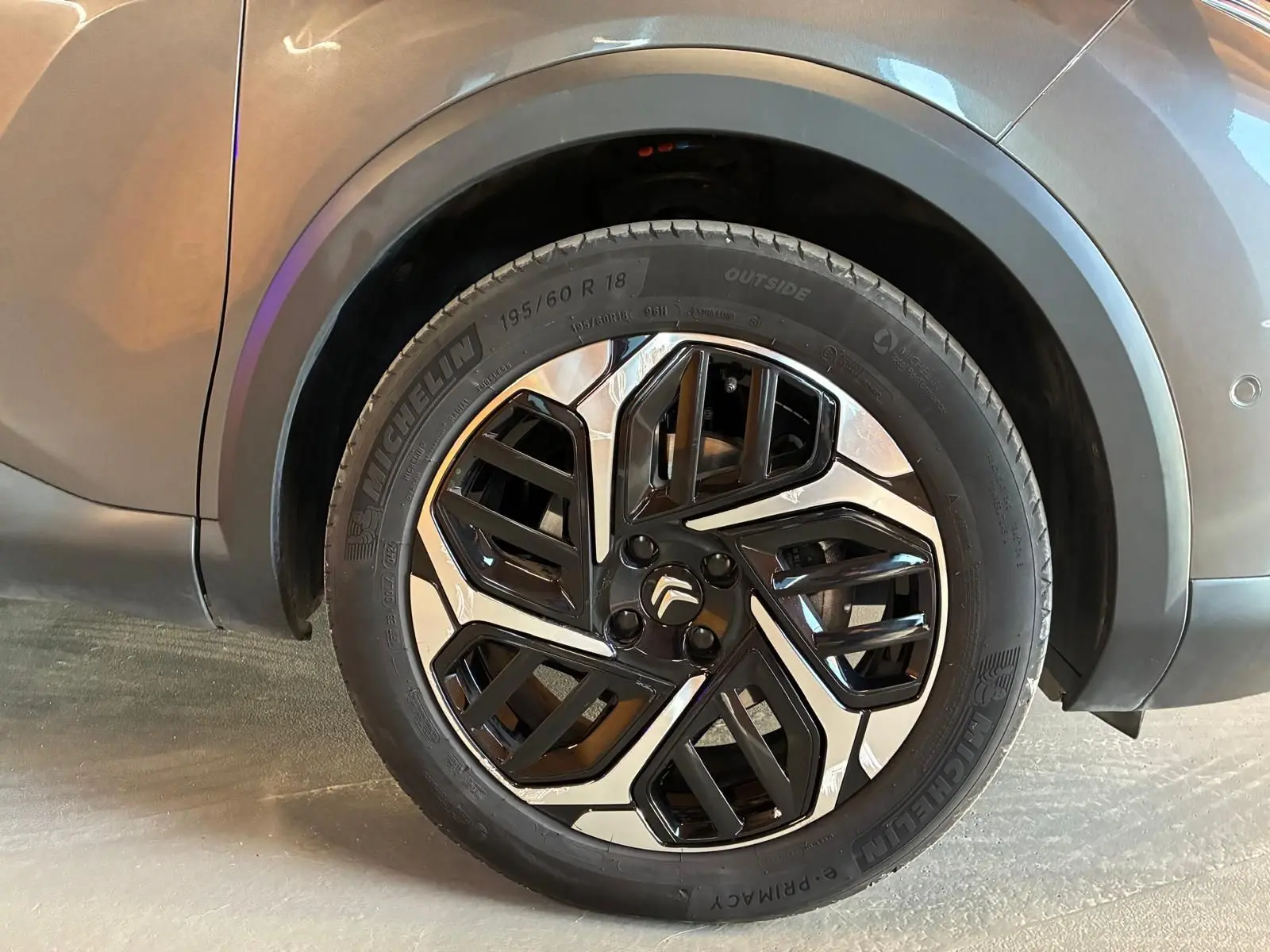 Gros plan sur la roue avant droite d’une Citroën C4 X gris, avec jante alliage bicolore et pneu Michelin.
