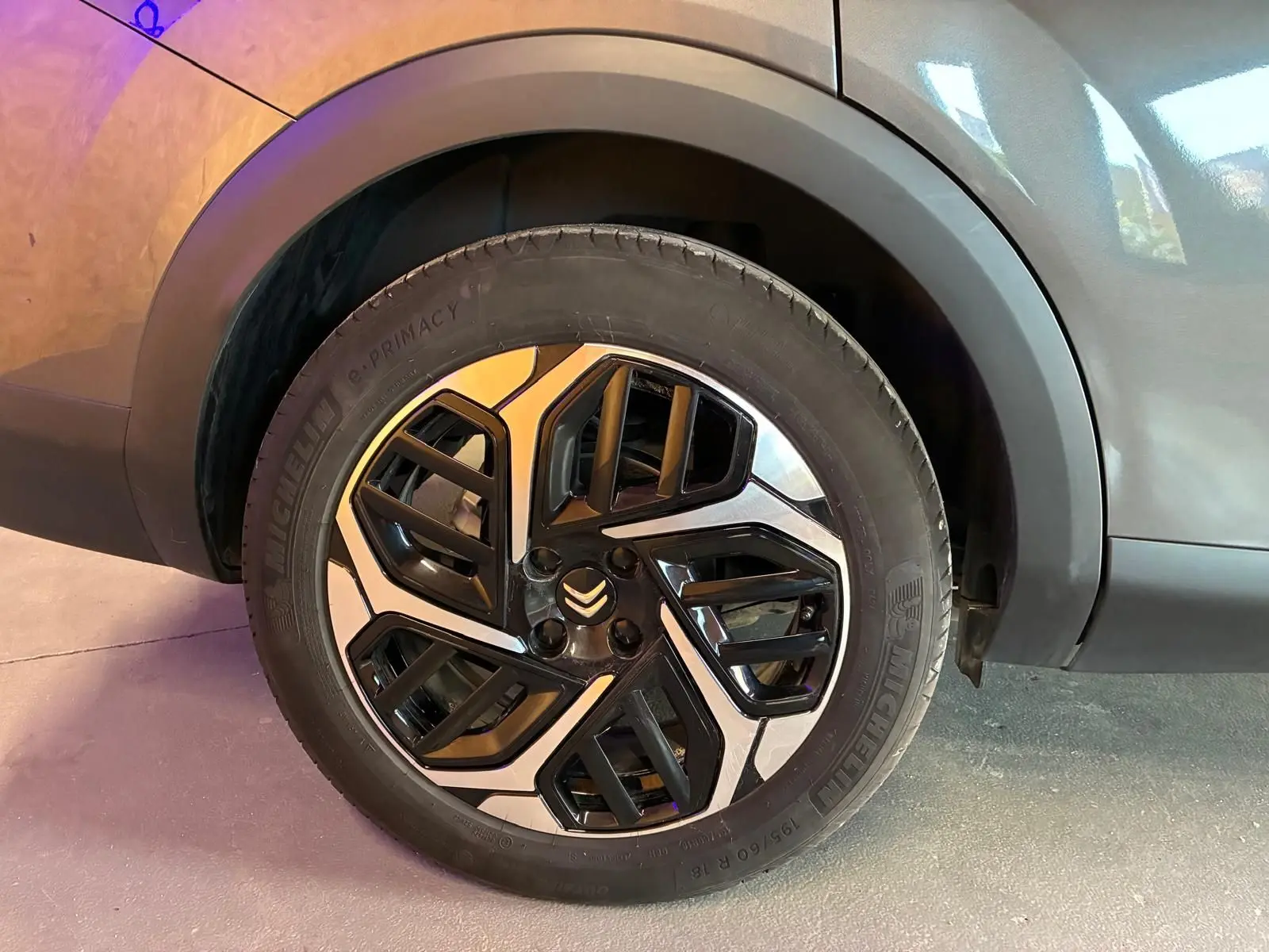 Gros plan sur la roue avant droite d'une Citroën C4 X gris 2024, mettant en valeur la jante noire et argentée au design géométrique.