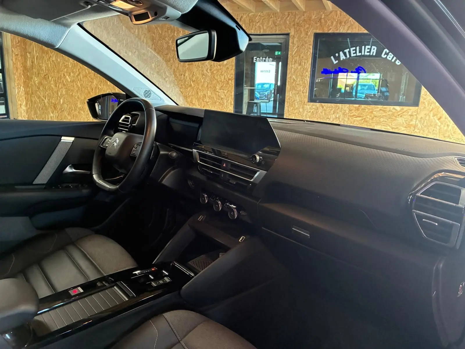 Vue intérieure côté conducteur du Citroën C4 X gris, mettant en valeur le tableau de bord moderne et le volant multifonction.