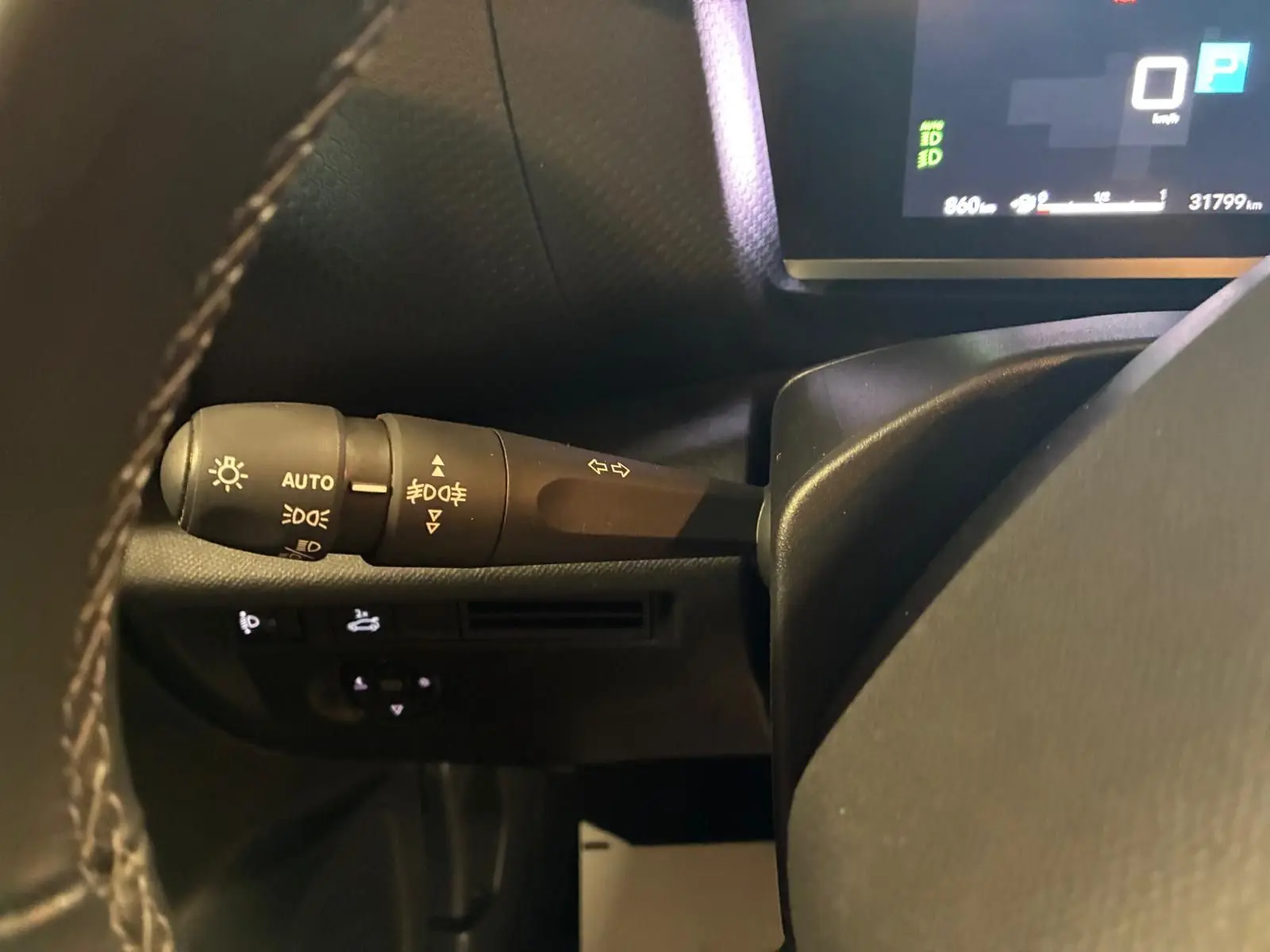 Gros plan sur la commande des feux à gauche du volant du tableau de bord d'une Citroën C4 X gris 2024.