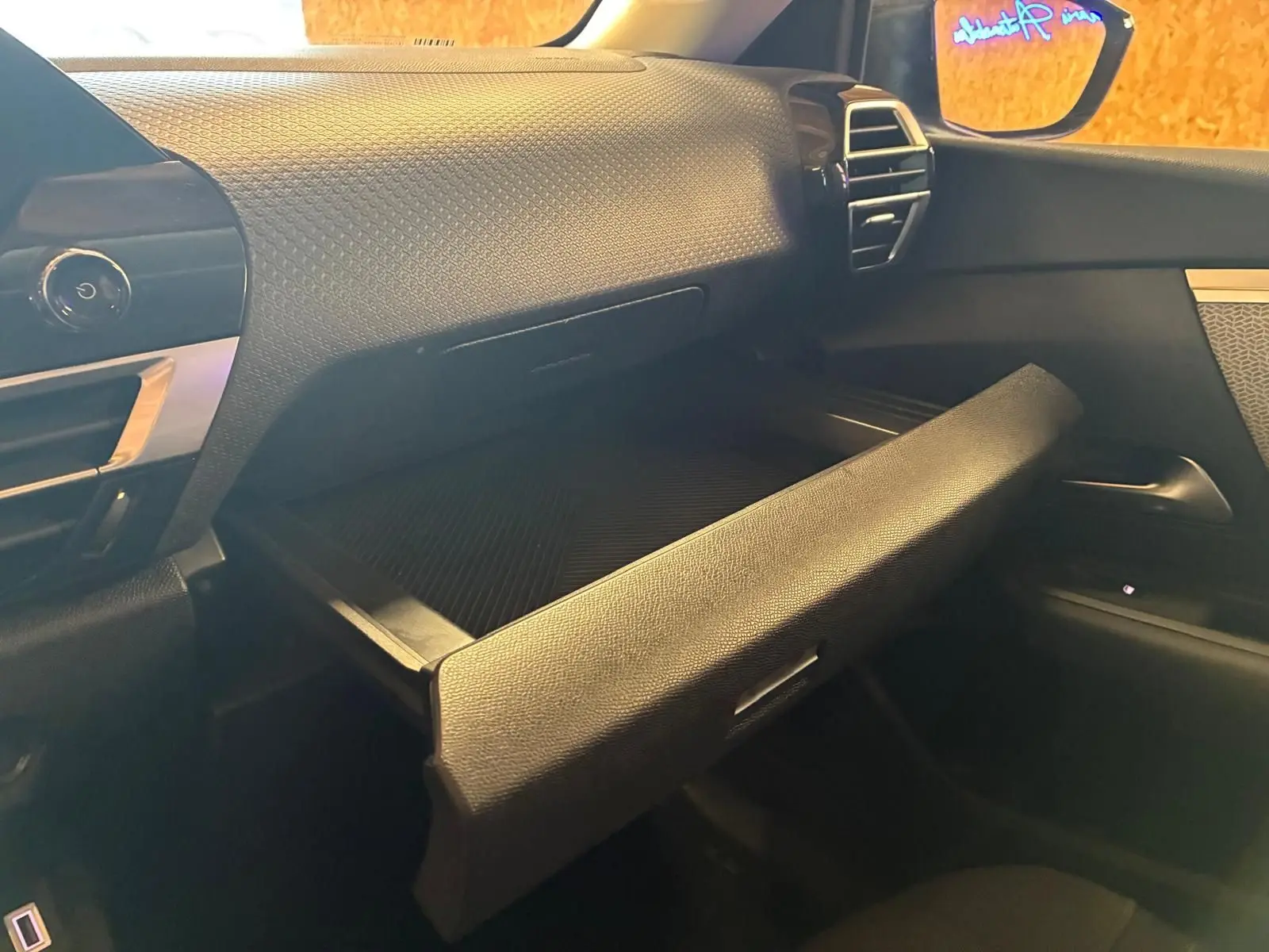Vue intérieure côté passager du coffre à gants ouvert du Citroën C4 X gris 2024, soulignant la texture du tableau de bord.