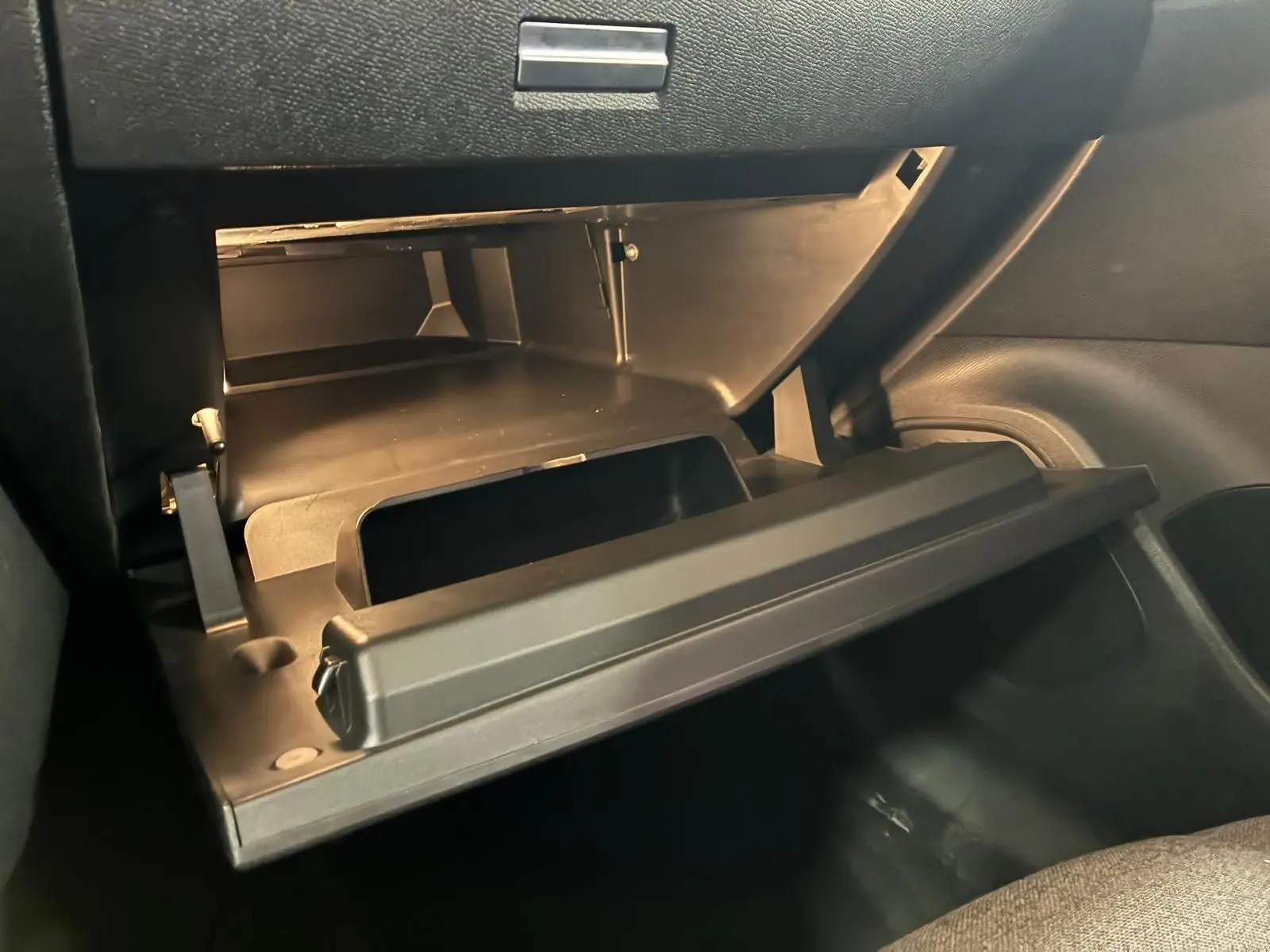 Vue intérieure du coffre à gants ouvert de la Citroën C4 X 1.5 BlueHDi 130 gris, montrant son espace de rangement.