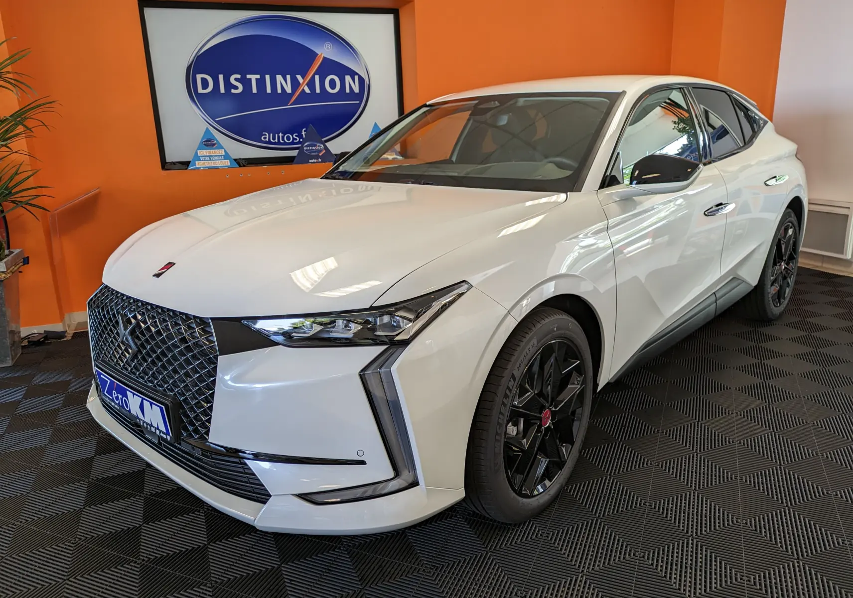 DS4 blanc nacré en 3/4 avant droit, avec calandre distinctive et jantes alliage noires 19 pouces.