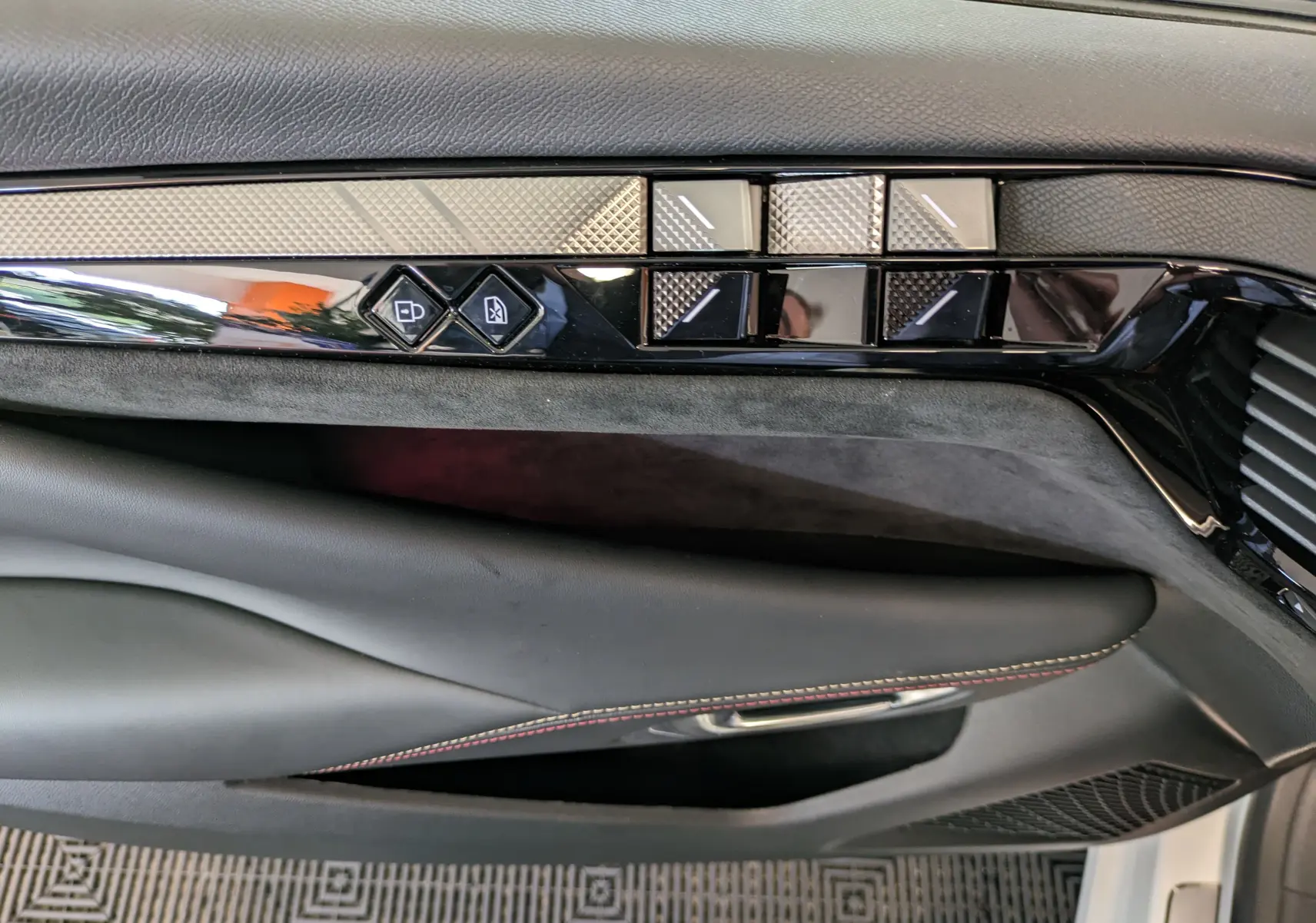 Détail de la garniture intérieure côté gauche de la porte d'une DS4 2024 avec inserts texturés et boutons de commande.
