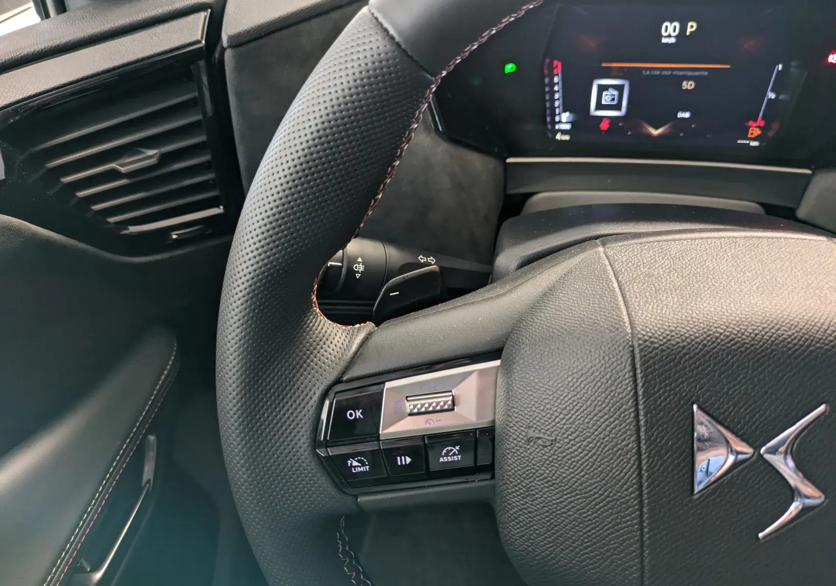 Vue rapprochée du volant en cuir perforé avec commandes intégrées du DS4 blanc nacré 2024, tableau de bord numérique visible.