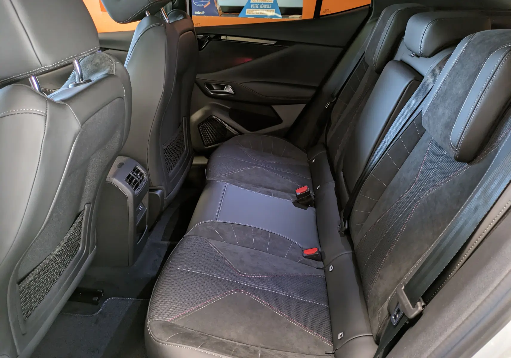 Vue intérieure arrière droite du DS4 2024 blanc nacré, mettant en valeur les sièges en tissu tressé Basalte avec Alcantara® et surpiqûres rouges.