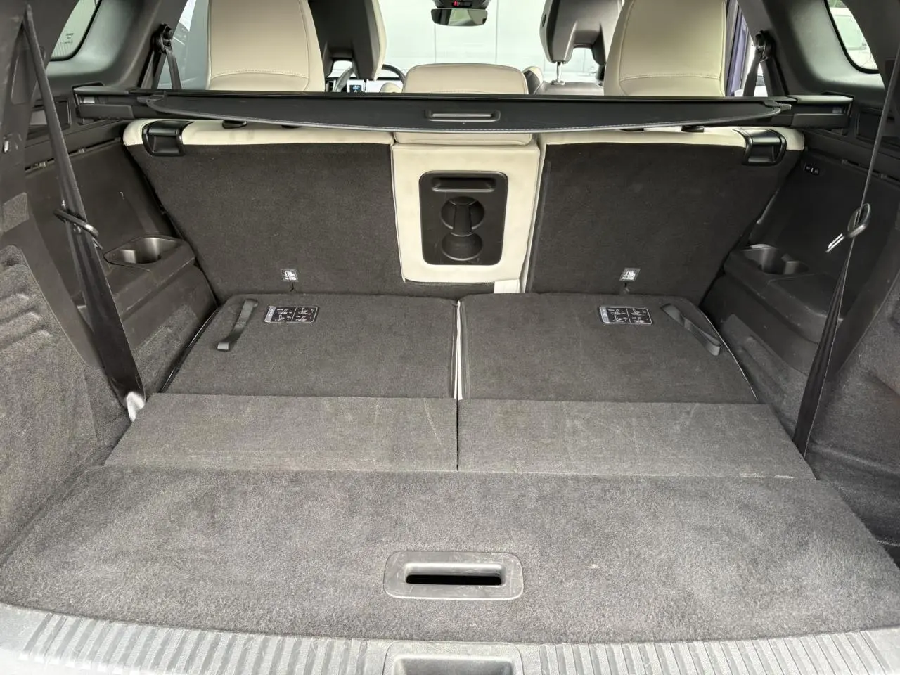 Coffre spacieux du Renault Espace E-Tech 2023 avec sièges arrière rabattus et sellerie claire visible à l'avant.