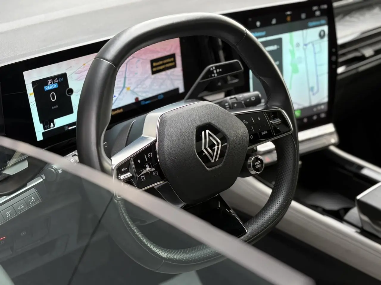 Vue rapprochée du volant cuir noir avec logo Renault et écrans numériques du tableau de bord du Renault Espace 2023.